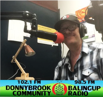 Photo of Neil Simpson wearing a hat behind a microphone at Donnybrook Community radio station